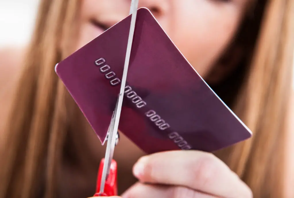 Close-up Of Hand Cutting Credit Card With Scissor